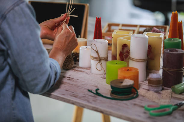 Shot of unrecognizable mature woman sitting at the table and crafting decorations for candles as a hobby.